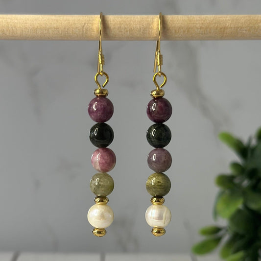 Crafted with a vibrant round tourmaline gemstone and freshwater pearl, these earrings are sure to garner attention. Stainless steel components provide a sparkle, lightweight and durable frame